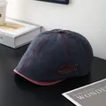 Détail d'une casquette en denim bleu avec coutures rouges et étiquette Natural - M / Bleu marine
