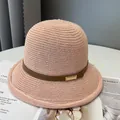 Cappello di paglia intrecciato rosa con cinturino in pelle e fibbia dorata su tavolo - M (56-58cm) / Rosa