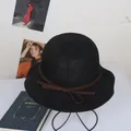 Detail of black woven straw sun hat with brown bow accent and wavy brim design - M / Black