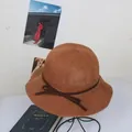 Detailed texture of brown woven straw hat with delicate bow and wavy brim design - M / Caramel color