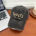 Nahaufnahme der gewaschenen schwarzen Baseballkappe mit TRUSTS-Stickerei auf Holztisch - M (56-58cm) / Schwarz