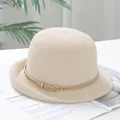 Detailopname van beige gebreide cloche hoed met leren riemgesp op een tijdschrift - M(56-58cm) / Beige
