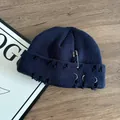 Detail of distressed navy knit beanie featuring metal rings and decorative safety pin - Navy Blue