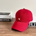 Berretto da baseball rosso con ricamo della lettera M bianca su scrivania in legno - M (56-58cm) / Borgogna