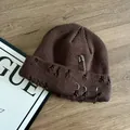 Dettaglio del berretto in maglia marrone scuro con anelli argentati, spilla e stile punk - M (56-58cm) / caffè