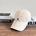 Dettaglio ravvicinato di un cappello beige in cotone con una lettera M ricamata blu notte - M (56-58cm) / Bianco Sporco