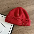 Dettaglio del berretto rosso in maglia con spille da balia punk e anelli d'argento - M (56-58cm) / Rosso