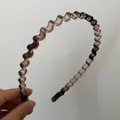 Detalle de diadema ondulada fina de resina marrón traslúcida con diseño minimalista moderno - Café Transparente