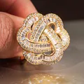 Anillo de flor hueca dorada con circonitas, vista de cerca sostenido en la mano - US 6 / Dorado
