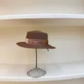 Detalle de un sombrero de paja marrón oscuro con cinta de satén y placa de logo dorada - M (56-58cm) / Café