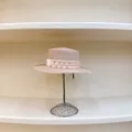 Detalle de sombrero de paja rosa con cinta de pedrería sobre un soporte de exhibición - M (56-58cm) / Rosa