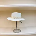 Detail of white straw boater hat featuring rhinestone ribbon on a silver display stand - M (56-58cm) / White