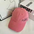 Detailed macro view of distressed pink cotton baseball cap with embroidered text and tag - M / Pink