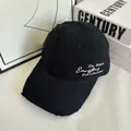 Dettaglio del ricamo bianco e dei bordi sfrangiati su un cappellino da baseball nero - M / Nero