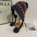 Detail of winter knit earflap hat with colorful diamond patterns and plush pom-poms - M (56-58cm) / Navy Blue