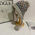 Detail of Fair Isle knit hat with pom-poms and earflaps on a wooden mannequin - M (56-58cm) / Gray