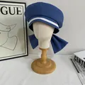 Navy blue sailor beret with white stripes and large bow decoration on light mannequin - M / Blue