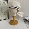 Detail view of cream sailor cap with back bow and decorative black trim on a mannequin - M / White