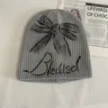 Detail of grey knitted beanie with black graffiti bow and Bleakleaf script embroidery - M (56-58cm) / Gray
