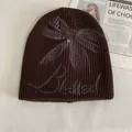Detail view of brown knit beanie featuring light gray butterfly graffiti and script text - M (56-58cm) / Coffee