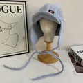 Dettaglio cappello aviatore in pile celeste con paraorecchie e toppa in pelle marrone - M / Blu