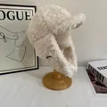 Detailed close-up of fluffy cream plush trapper hat with Heather label on a wooden stand - M(56-58cm) / White
