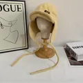 Colbacco in peluche giallo tenue con paraorecchie e lacci su testa di manichino in legno - M / Giallo
