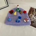 Détail du bonnet en maille violet clair avec mini breloques gants et chapeaux colorés - Violet