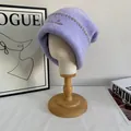 Detalle de la textura del gorro de punto lila con costuras marrones y bordado fino - M / Púrpura