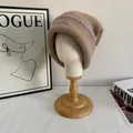 Detalle de gorro de punto marrón con bordado azul claro y ribete morado cosido a mano - M / Caqui
