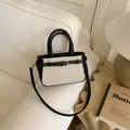 Detail of contrast stitching and black leather trim on minimalist cream fabric handbag - Black