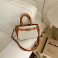 Chic cream canvas square bag with brown leather trim and metal buckle on sofa - Brown