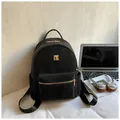 Minimalist black backpack with gold hardware displayed in a modern lifestyle workspace - Black