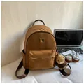 Detail of a brown suede backpack with gold zippers and a cute plush bear charm accessory - Brown