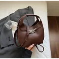 Detail of dark brown litchi pattern leather bucket bag with silver metal swivel lock - Coffee