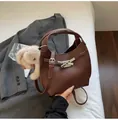 Detail of a brown textured bucket bag with silver metal buckle and plush animal charm - With Pendant / Coffee