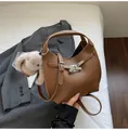 Detail of caramel brown litchi grain leather bucket bag with silver buckle and plush charm - With Pendant / Brown