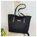 Detail of black corduroy tote bag showing textured fabric and leather handles with gold rivets - Black