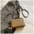 Detalle de bolso en cuero granulado caqui con doble cremallera plateada sobre fondo de traje - Sin colgante / Gris