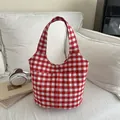 Rot-weiße Gingham-Einkaufstasche mit Vordertaschen auf einem Sofa in gemütlichem Heim - Rot