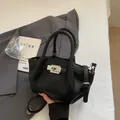 Black litchi-grain leather bucket bag with silver twist lock and adjustable strap - Black Without Charm