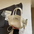 White pebbled leather bucket bag with silver twist lock and adjustable shoulder strap - White Without Charm