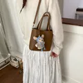 Detailed view of brown lychee leather handbag with a cute teddy bear charm on model - With Pendant / Brown