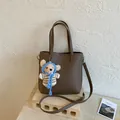 Gros plan du sac cabas marron foncé à texture litchi avec un joli porte-clés ours - Sans pendentif / Gris