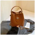 Detail of lychee textured brown bucket bag with silver cross-shaped metal lock - No Pendant / Brown