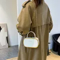 Sac boîte rétro blanc avec cadre doré et poignée tressée sur un trench-coat chic - Milky blanc
