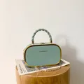 Detail view of mint green box clutch with gold metal frame and fashion text branding - Light Green