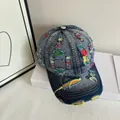 Dettaglio del cappellino in denim lavato con ricami colorati ed effetti strappati - M (56-58cm) / Azzurro