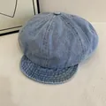 Detailopname van lichtblauwe denim krantenjongenspet met knoop op witte ondergrond - M / Lichtblauw