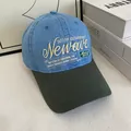 Detail van Newave-borduurwerk op een blauw en olijfgroen patchwork denim baseballcap - M / Hemelsblauw